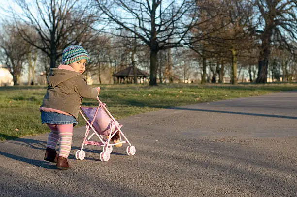 Photo of Child pushing her own baby troller