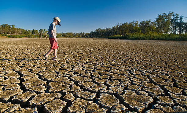 Young boy walking on a dry lake bed looking down