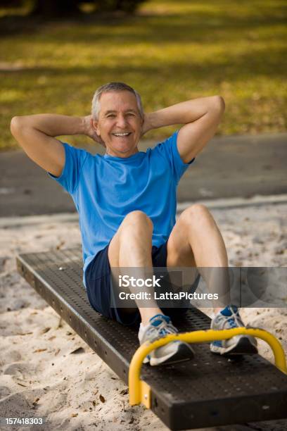 Uomo Anziano Seduto Sulla Panchina Facendo Crunch Al Park - Fotografie stock e altre immagini di Abbigliamento sportivo