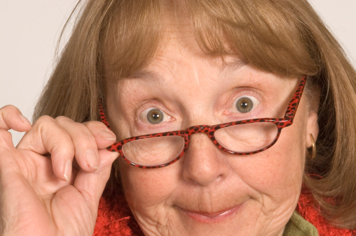 Close up of a senior adult female wearing glasses pursing her lips in disapproval at the camera.  This senior citizen wants to tell the viewer exactly what she thinks, because her opinion should be just as important as yours!