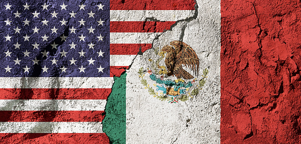 Cooperation or conflict? National flags of the United States and on a cracked, textured plastered wall, representing diplomacy, trade or geopolitics.