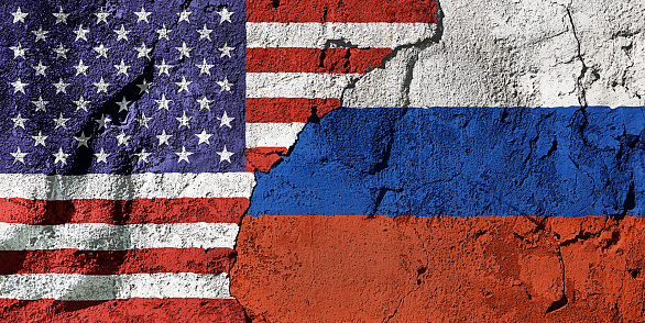 Cooperation or conflict? National flags of the United States and Russia on a cracked, textured plastered wall, representing diplomacy, trade or geopolitics.
