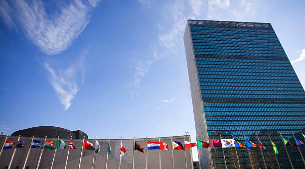 United Nations Building with Flags Colorful flags of the world, blowing in the wind in front of the United Nations UN Building.  Plenty of room for your text. 42nd street photos stock pictures, royalty-free photos & images