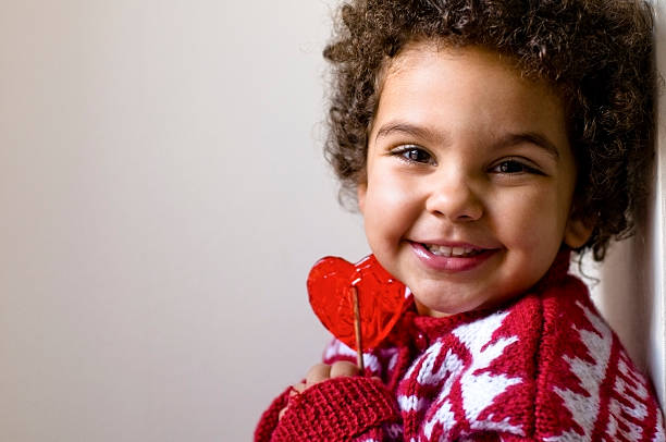 Criança feliz, segurando a tensão seu coração em forma de Pirulito - foto de acervo
