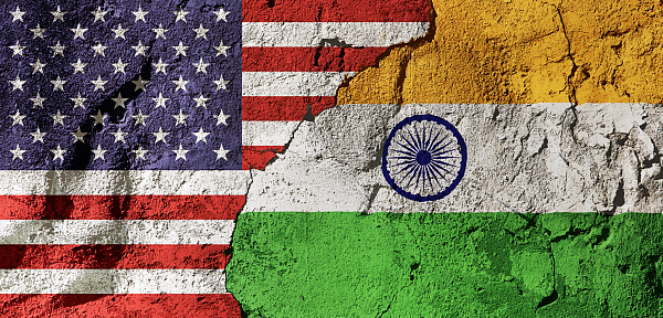 Cooperation or conflict? National flags of the United States and India on a cracked, textured plastered wall, representing diplomacy, trade or geopolitics.
