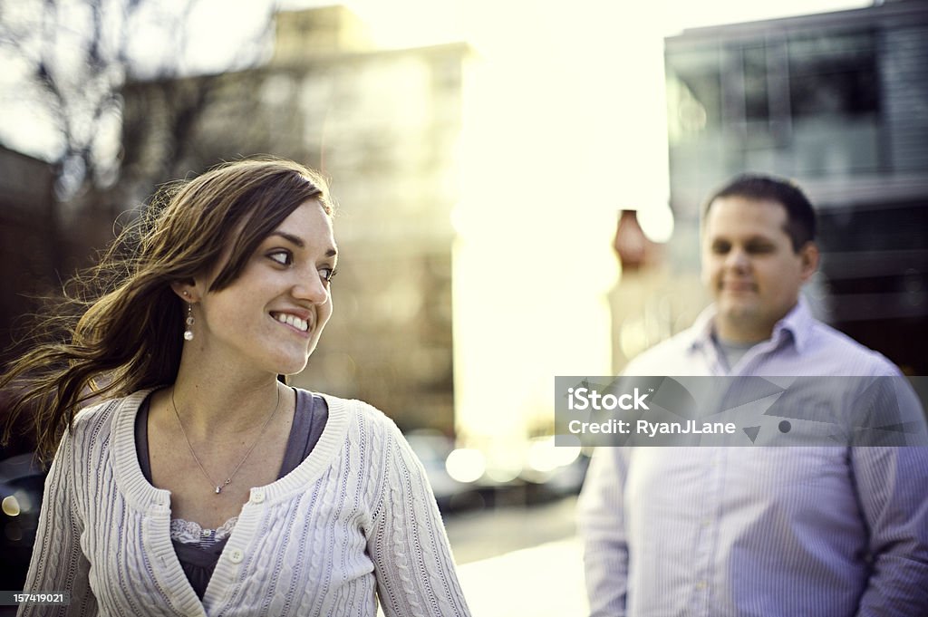 Urban Setting and Young Couple In Love A young woman gives her man a pleasant smile over shoulder while walking downtown in Portland, OR. 18-19 Years Stock Photo