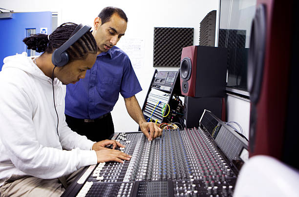further education: teacher and pupil on recording studio mixing desk stock photo