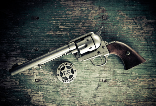 us marshal badge and gun over a peeled wooden background