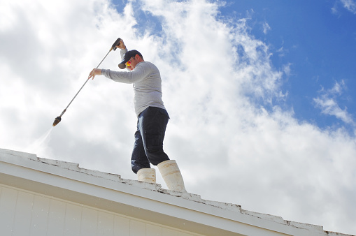 Handy man Pressure cleaning a roof.