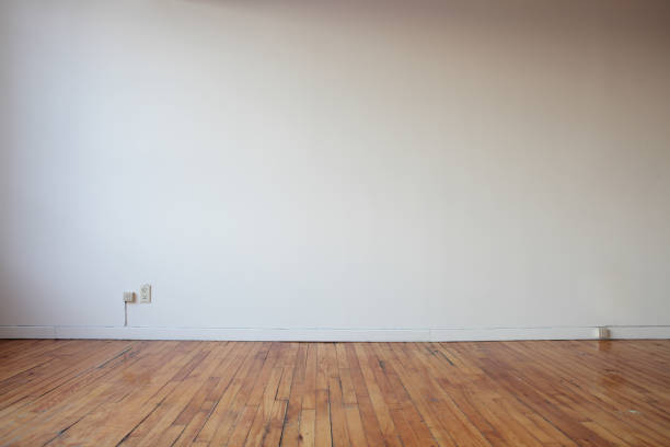 Wide angle interior shot of an empty room with a timber window, wood floors and curtains. View to outside is of a wooden fence.