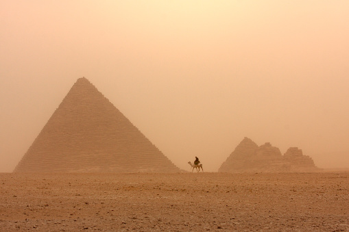 The sun sets over the pyramids of Giza, the camel caravan passes