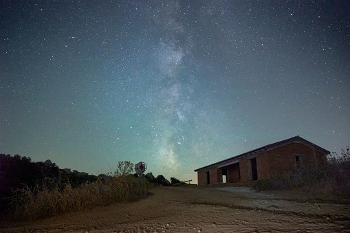 A scenic view of a rural barn illuminated by the night sky filled with stars