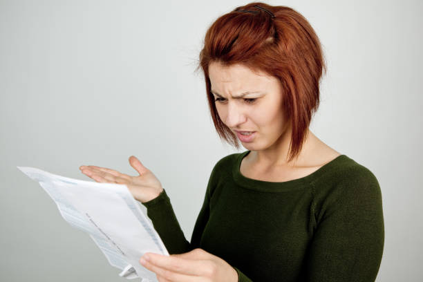 disbelieved frau blick nach unten auf der kreditkartenabrechnung - unemployment fear depression women stock-fotos und bilder