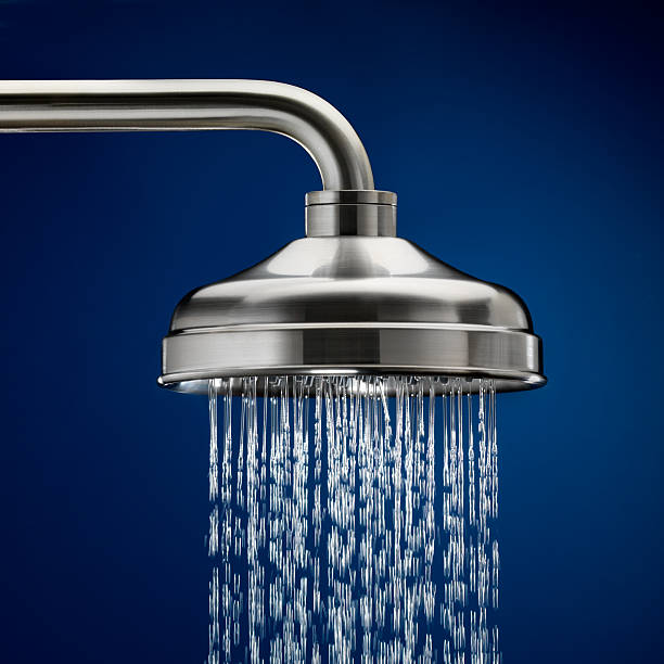 Shower head with streaming water, blue background stock photo