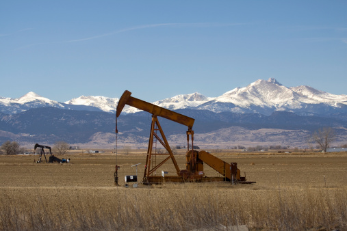 Oil pumpers stand idle on farmlands in Weld county, with the 14255 foot Longs Peak and Mount Meeker in the background, Colorado.