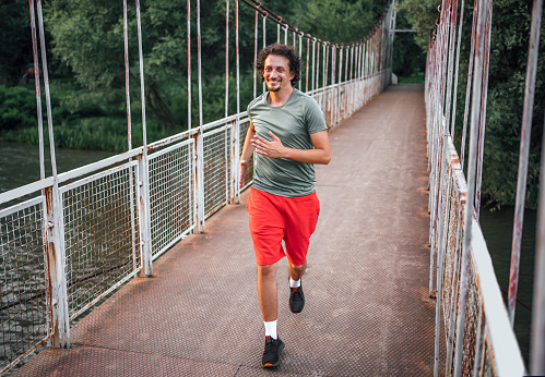 Cheerful young man in sportswear running outdoors