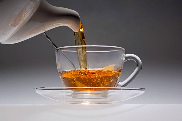 tè bianco versare da una pentola in una tazza di vetro cina. - noggin foto e immagini stock