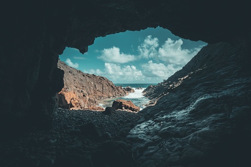 Cave on a rocky shoreline illuminated by sunlight streaming into the ocean