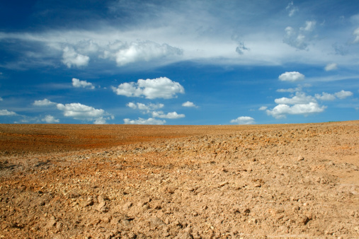 Photo of a arid and desert place, with a blue and cloudy sky.