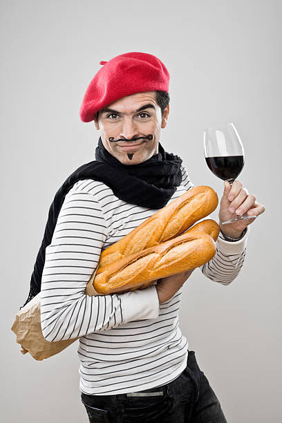 French Baguettes And Wine A French man in a red beret carrying French baguettes and holding a glass of red wine. beret stock pictures, royalty-free photos & images