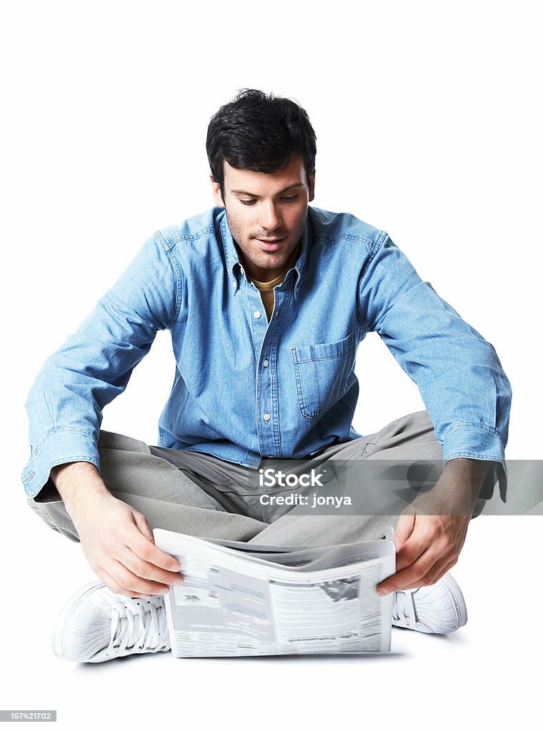 Homem Jovem sentado no chão lendo jornal - Foto de stock de Ler royalty-free