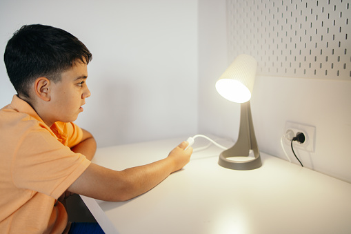Boy turning on the lamp in his room