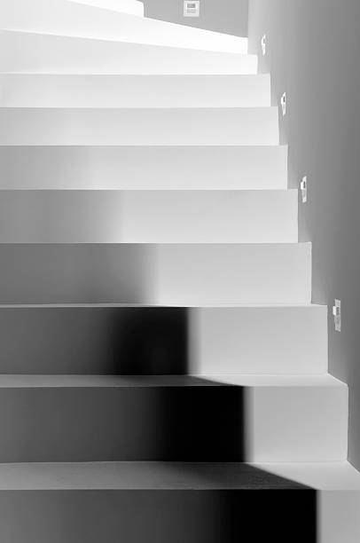 Silhouette shadow of person legs walking up the public stairs in subway passage on the night in black and white
