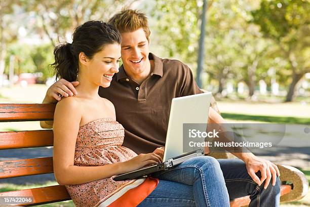 Smiling Young Couple Using Laptop At Park Stock Photo - Download Image Now - 20-24 Years, Adult, Adults Only