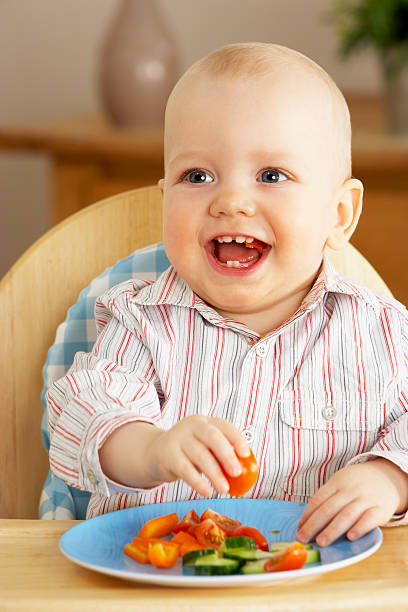 Young Boy Enjoying Snack In High Chair stock photo