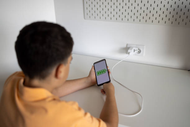 istock Boy turning on mobile phone after charging batteries 1574223221