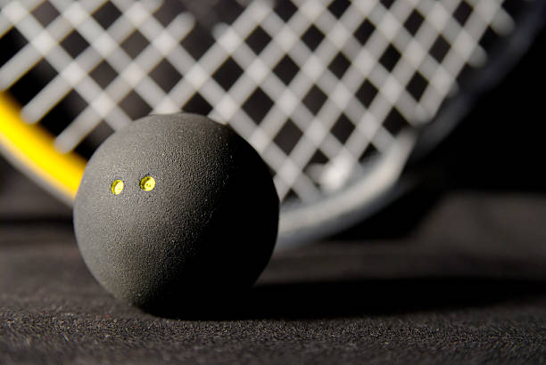 squash ball und schläger auf schwarz - squash racket stock-fotos und bilder