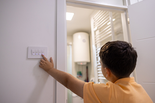 Shot of a little boy turning off an electrical switch