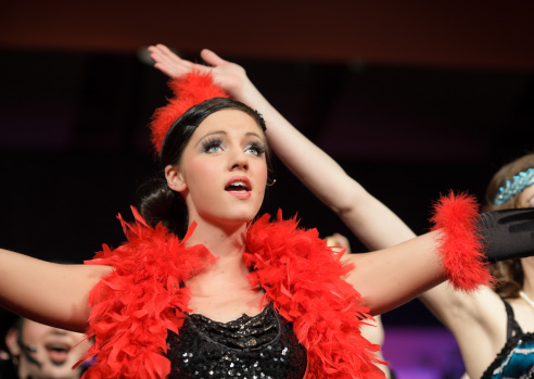 Opera singer performing on the stage  of the alternative art club. She is wearing period costume.