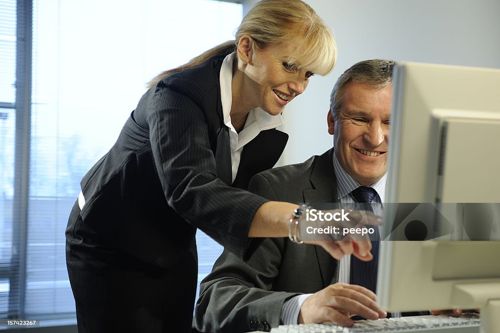 Sonriendo negocios dos personas mirando a un ordenador en su oficina. - Foto de stock de 30-39 años libre de derechos
