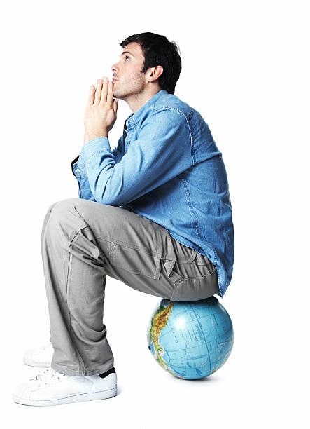 jeune homme assis dans globe prier - human hand earth praying moving up photos et images de collection