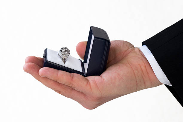 istock Groom's hand offering diamond engagement ring, close-up, wedding 157423438