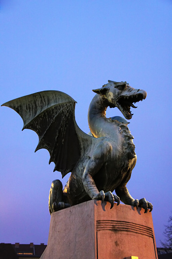 The popular silver and red dragon statue on a  London street with no people and traditional English building in the background. The dragon has a red tongue and holds a shield.