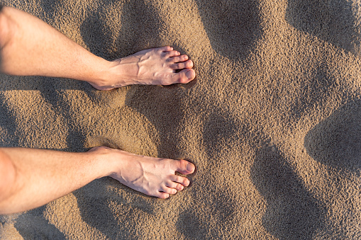 Rear view of feet walking along path on desert dunes