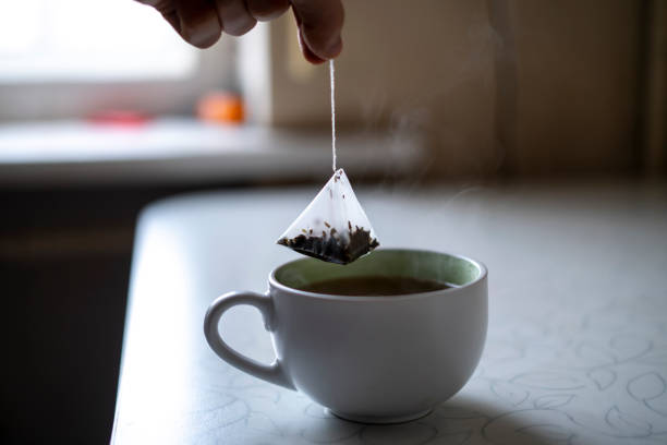 istock person's hand holding a tea bag and making hot cup of tea 1574238028