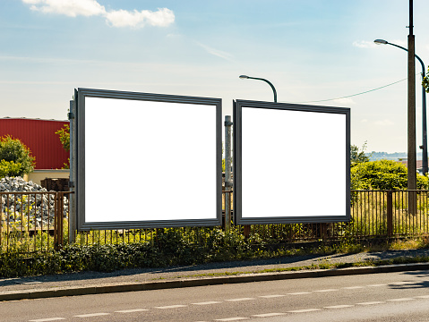 Two blank billboard mockups next to each other. Advertisement template next to a street in an industry district of a big city. The space is free to insert any graphics. The road is empty.