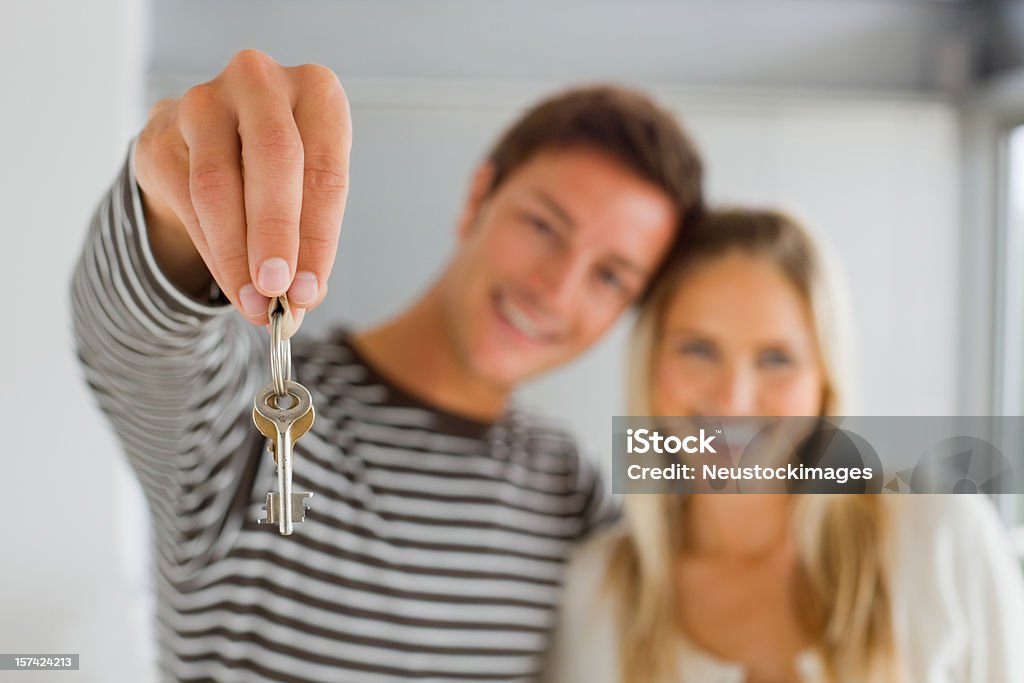 Młody człowiek trzyma klucze i kobieta stojąc razem - Zbiór zdjęć royalty-free (Klucze do domu)