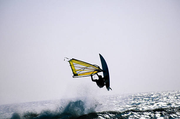 Water Sport Activity - Windsurfer Riding a Wave in Rough Sea on a Windy Day.