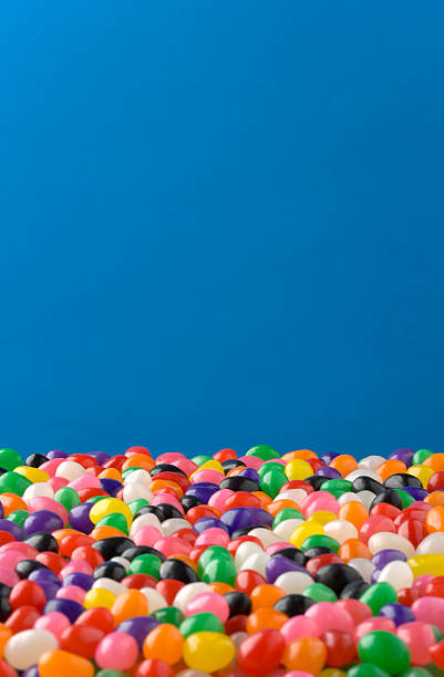 Jelly Beans against blue background, nice for Easter Jellybeans fill the lower 1/3 of the frame, Jellybeans in front are out of focus, those in back are in focus. Clipping Path around Jellybeans so the blue can be removed or changed. jellybean stock pictures, royalty-free photos & images