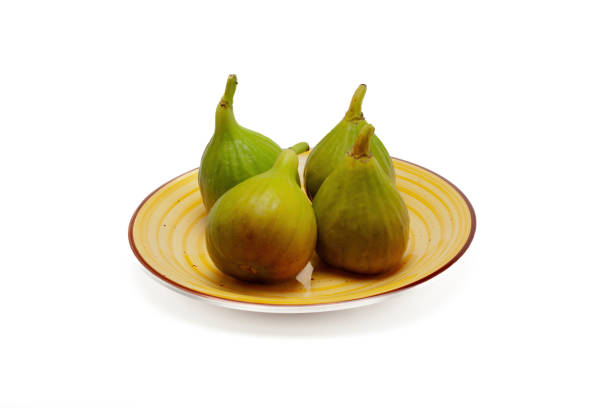 istock Four green figs on a yellow plate 1574248545