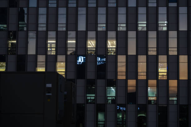 istock Offices seen through illuminated windows after sunset, modern city night view with reflections in architecture 1574250733