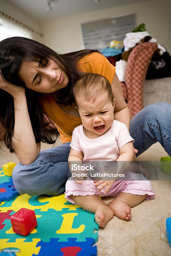 Baby girl crying with depressed mom behind her  Mother Stock Photo