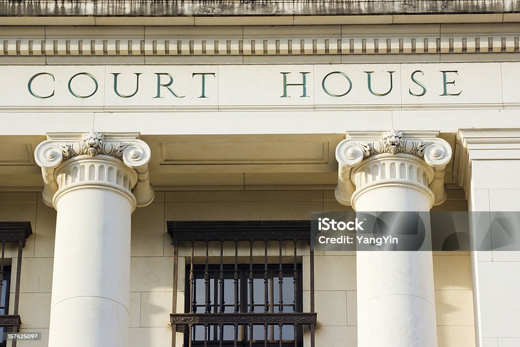 Courthouse Sign and Architectural Columns of Legal System Building Exterior Horizontal detail view of a government law building, featuring stylized ionic architectural columns with lion heads and filagree capitals, entablature with “Court House” lettering in all-caps Roman letters, and iron grill barred-over windows. This justice building exterior shows security protection used in the legal system of San Antonio, Texas, U.S.A.   Courthouse Stock Photo