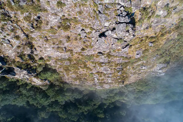 aerial top view of a mountain cliff on a misty day
