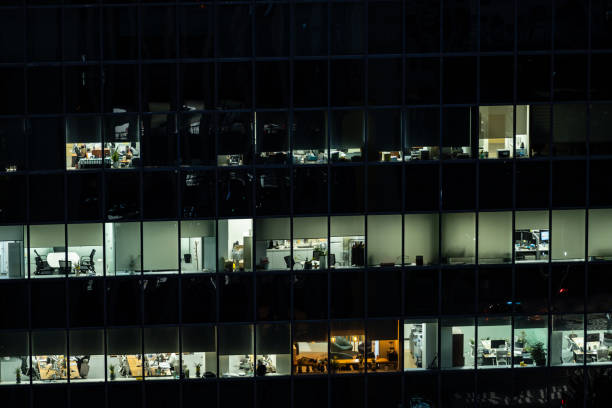 istock Offices seen through illuminated windows after sunset, modern city night view with reflections in architecture 1574251276