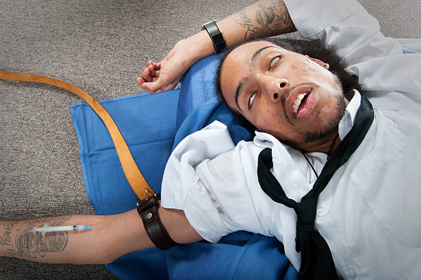 Drug Abuse A model imitates the actions of a heroin addict. drug addiction tattoos stock pictures, royalty-free photos & images
